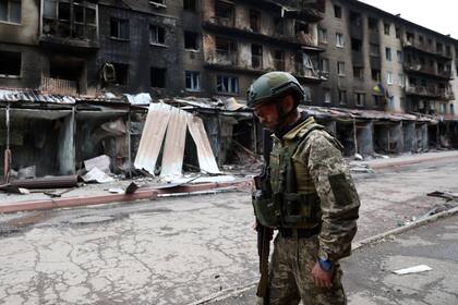 Un soldado ucraniano con el fondo de destrucción urbana que provoca la guerra en todo el país