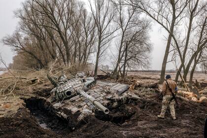 Un soldado ucraniano mira un tanque ruso destruido cerca de la aldea de Zavorychi