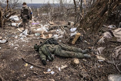 Un soldado ucraniano pasa junto al cuerpo de un soldado ruso tendido en el suelo después de que las tropas ucranianas retomaran el pueblo de Mala Rogan, al este de Kharkiv, el 30 de marzo de 2022

