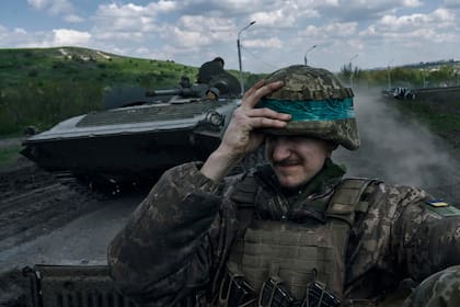 Un soldado ucraniano se agarra el casco mientras viaja a bordo de un APC en Bájmut, en la provincia ucraniana de Donetsk, el 26 de abril de 2023 (AP Foto/Libkos)