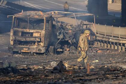 Un soldado ucraniano se desplaza entre los restos de un camión militar incendiado en una calle en Kiev.