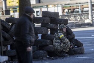 Un soldado ucraniano se protege detrás de los neumáticos en el barrio de Zhuliany de Kiev.