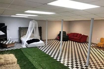 Un sótano ambientado como dormitorio, living y espacio verde con sintético