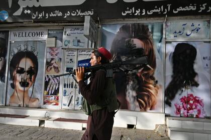 Un talibán pasa frente a un salón de belleza, que fue vandalizado