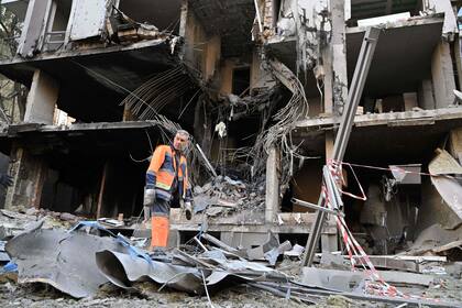 Un trabajador comunal se encuentra entre los escombros frente a un edificio dañado en Kiev el 29 de abril de 2022, en medio de la invasión rusa de Ucrania. 