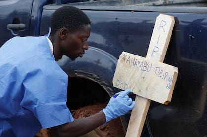 Un trabajador de la cruz roja congoleña escribe en una cruz el nombre de Kahambu Tulirwaho, quien murió de ébola, antes de su entierro en un cementerio en Butembo, en el Congo