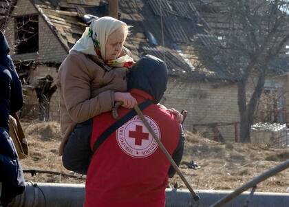Un trabajador de la Cruz Roja traslada a una anciana durante la evacuación de Irpín, a unos 25 kms (16 millas) al noroeste de Kiev, el 11 de marzo de 2022. (AP Foto/Efrem Lukatsky)