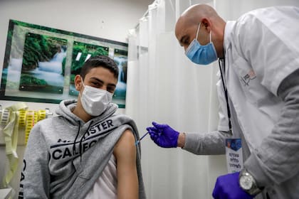 Un trabajador de la salud administra una dosis de la vacuna Pfizer-BioNtech a un hombre en los Servicios de Salud de Clalit en el barrio palestino de Beit Hanina, en el este de Jerusalén