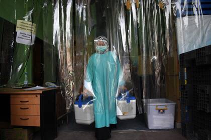 Un trabajador de la salud entrega contenedores de vacunas Covid-19 producidas por Sinovac de China, desde una cámara fría en Bandung el 13 de enero de 2021