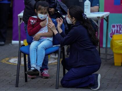 Un trabajador de la salud inocula a una niña contra el COVID-19 en la escuela Providencia en Santiago, Chile, el lunes 27 de septiembre de 2021, durante el inicio de la vacunación en escuelas para niños de 6 a 11 años. 