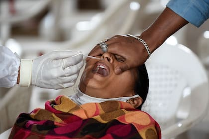 Un trabajador de la salud que usa un equipo de protección personal toma una muestra de hisopado de una mujer en un campo de pruebas en Sanathal, India, el 30 de agosto de 2020