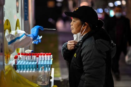 Un trabajador de la salud toma una muestra de hisopo de una mujer para analizar el coronavirus Covid-19 en el distrito de Huangpu en Shanghái el 19 de diciembre de 2022.