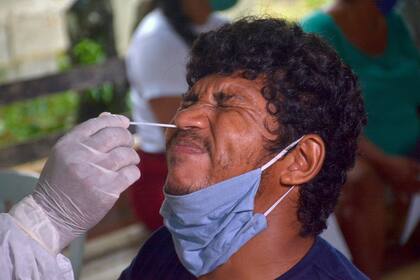 Un trabajador de la salud toma una muestra de hisopado de un hombre en la comunidad ribereña de Bela Vista do Jaraqui, Manaus, estado de Amazonas, Brasil, el 18 de enero de 2021