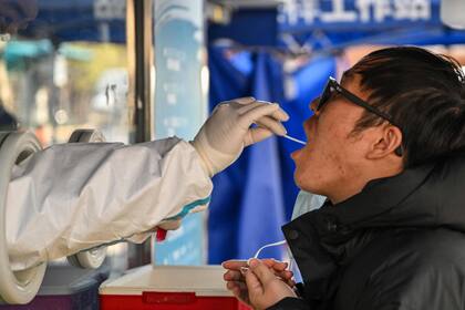 Un trabajador de la salud toma una muestra de hisopo de un hombre para analizar el coronavirus Covid-19 en el distrito de Jing'an en Shanghái el 22 de diciembre de 2022