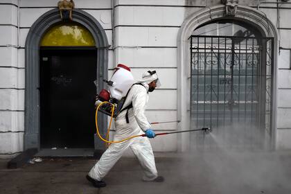 Un trabajador de limpieza con equipo de protección personal desinfecta una calle de la Ciudad de México, el 7 de mayo de 2020, en medio de la pandemia de coronavirus