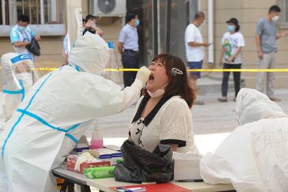 Un trabajador de salud realiza una prueba de coronavirus en un residente en un centro de pruebas improvisado en Dalian, en la provincia de Liaoning, noreste de China, el 28 de julio de 2020