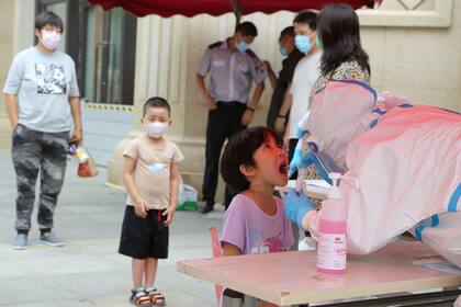 Un trabajador de salud realiza una prueba de coronavirus en un niño en un centro de pruebas improvisado en Dalian, en la provincia de Liaoning, noreste de China, el 27 de julio de 2020