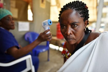 Un trabajador de salud verifica la temperatura de una mujer como parte de la prueba de detección del ébola al ingresar al Hospital General en Goma, República Democrática del Congo