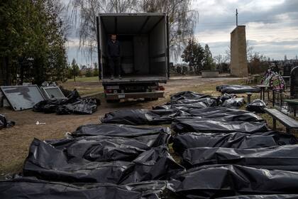 Un trabajador del cementerio espera en un camión antes de que sus colegas comiencen a cargar los cadáveres de los civiles asesinados en Bucha, para transportarlos a la morgue.