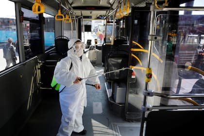Un trabajador en un traje de protección desinfecta un autobús debido a preocupaciones de coronavirus en Estambul, Turquía 