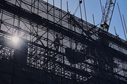 Un trabajador instala andamios en un edificio en construcción en un distrito comercial de la capital, en Beijing, el martes 21 de octubre de 2025. (AP Foto/Andy Wong)