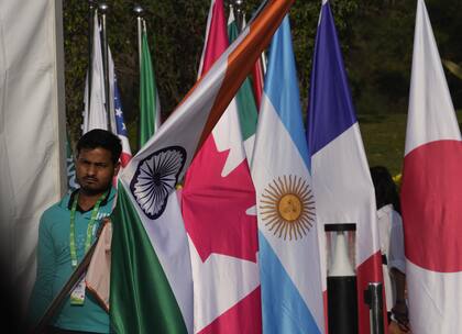 Un trabajador lleva la bandera de la India para colocarla junto a las de otros países participantes en la sesión inaugural de la reunión de ministros de Relaciones Exteriores del G20 en Nueva Delhi, India.