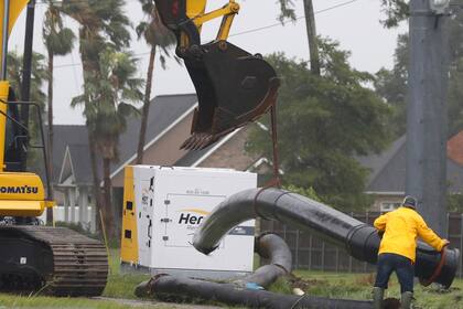 Un trabajador maniobra una sección de una tubería mientras una cuadrilla trabajaba para instalar bombas de drenaje en el oeste de Morgan