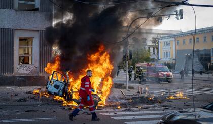 Un trabajador médico pasa por delante de un coche en llamas tras un ataque ruso en Kiev, Ucrania, el lunes 10 de octubre de 2022.