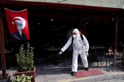 Un trabajador municipal con traje de protección desinfecta una cafetería en el distrito de Karaagac en Turquía, cerca de la frontera con Grecia