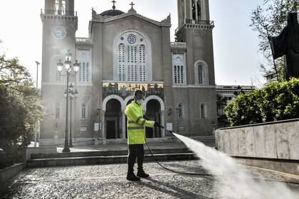 Un trabajador municipal desinfecta la explanada frente a la Iglesia Metropolitana de Atenas