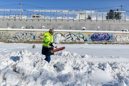 Un trabajador palea en una autopista después de una tormenta de nieve, en Atenas, el martes 25 de enero de 2022