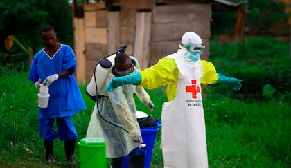 Un trabajador sanitario le rocía desinfectante a su colega tras trabajar en un centro de tratamiento del ébola en Beni, en el este de la República Democrática del Congo, el 9 de septiembre de 2018 (AP Foto/Al-hadji Kudra Maliro, Archivo)