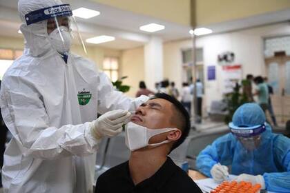 Un trabajador sanitario realiza un hisopado a un hombre en el Centro de Control y Prevención de Enfermedades en Hanói el 22 de mayo
