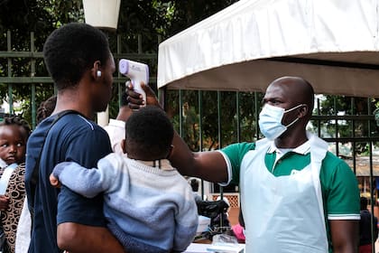 Un trabajador sanitario usa un termómetro para revisar la temperatura de las personas frente al Hospital Musulmán Kibuli en Kampala, Uganda