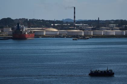 Un transbordador cruza la bahía de La Habana frente a la refinería de petróleo Nico López, donde está anclado un petrolero cubano
