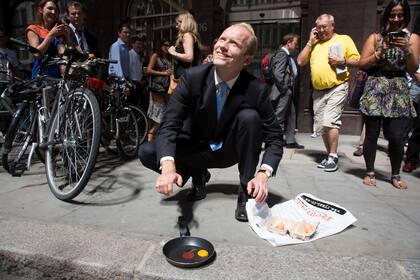 Un transeúnte trata de freír un huevo frente al "Walkie Talkie" en la ciudad de Londres después de que la luz del sol reflejada desde el edificio derritiera un auto