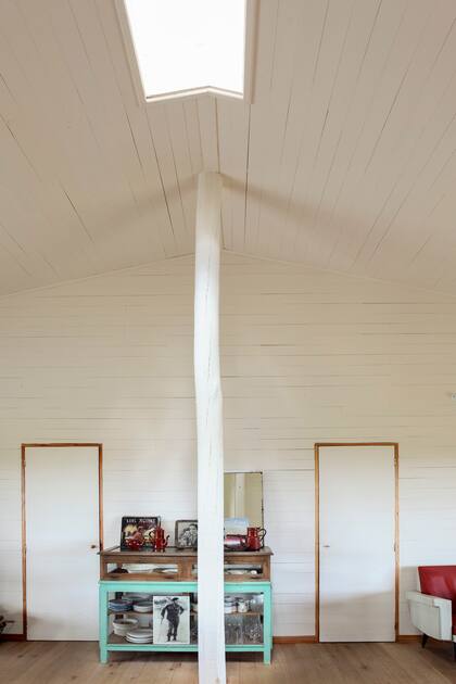 Un tronco de eucalipto tratado y pintado sostiene el punto más alto del techo a dos aguas sin entorpecer la circulación y remata en una lucarna que trae luz cenital.