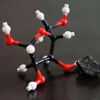 Un trozo del meteorito Murchison, junto a la estructura molecular la ribosa, uno de los azúcares hallados en su polvo