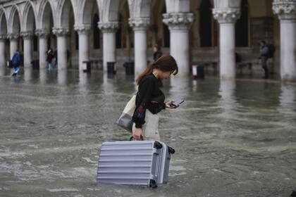 Un turista lleva su equipaje en una plaza inundada de San Marcos, en Venecia