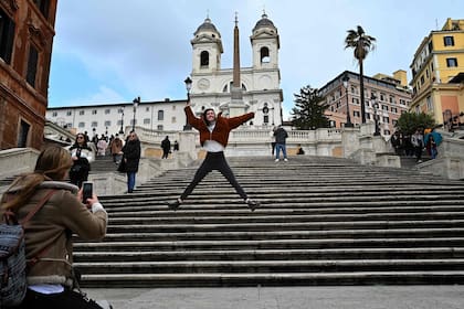 Un turista posa para una foto frente a la Plaza de España vacía en el centro de Roma, el 3 de marzo de 2020. Italia instó a los turistas asustados por el coronavirus a que no se mantuvieran alejados, pero los esfuerzos para tranquilizar al mundo que estaba manejando el brote se vieron ensombrecidos 