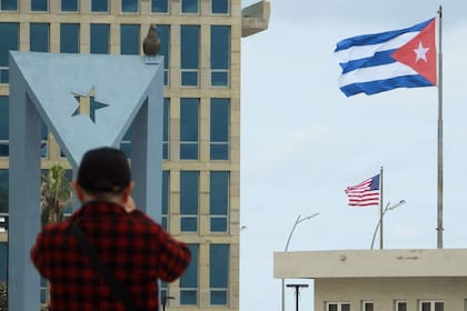 Un turista toma fotos de la Embajada de Estados Unidos, con las banderas de Estados Unidos y Cuba al fondo