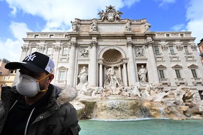 Un turista usa un barbijo frente a la Fontana de Trevi en el centro de Roma, el 3 de marzo de 2020. En Roma, lejos de los puntos críticos del norte, más del 50 por ciento de las reservas se cancelaron hasta finales de marzo, dijo la asociación de hoteles Federalberghi.