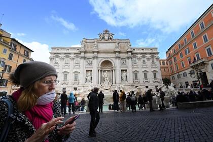 Un turista usa un barbijo mientras camina frente a la Fontana de Trevi en el centro de Roma, el 3 de marzo de 2020.