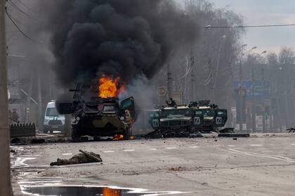 Un vehículo blindado de transporte de personal ruso arde en medio de vehículos utilitarios ligeros dañados y abandonados después de los combates en Kharkiv, Ucrania, el domingo 27 de febrero de 2022.
