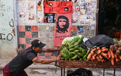 Un vendedor ambulante de verduras pasa frente a un local de souvenirs con la imagen icónica del Che Guevara en La Habana