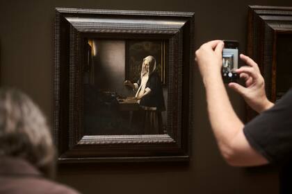 Un visitante fotografía "Woman Holding a Balance", de Vermeer, en la Galería Nacional de Arte de Washington. Varias obras atribuidas al pintor holandés están actualmente en estudio 