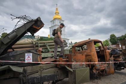 Un zapador inspecciona un vehículo ruso dañado instalado como símbolo de guerra en el centro de Kyiv, Ucrania, el jueves 15 de junio de 2023.