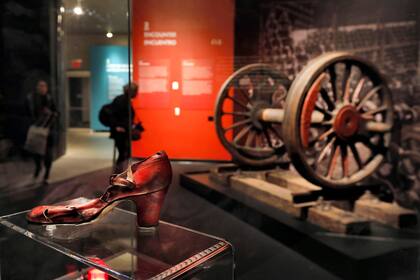 Un zapato encontrado en Auschwitz, y a la izquierda, un par de ruedas de una locomotora de carga alemana se muestran en la exhibición "Auschwitz: No hace mucho, no tan lejos"