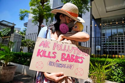 Una activista muestra un cartel con una muñeca que representa a los bebés afectados por la contaminación aérea, durante una protesta ante la Corte del Distrito Central de Yakarta, donde se dirimía una demanda contra autoridades indonesias por no mejorar la calidad del aire, el 16 de septiembre de 2021. El cartel dice "La polución aérea mata (especialmente) bebés". (AP Foto/Dita Alangkara)