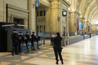 Una agente de policía toma una fotografía de sus colegas en la estación de tren de Constitución que está vacía
